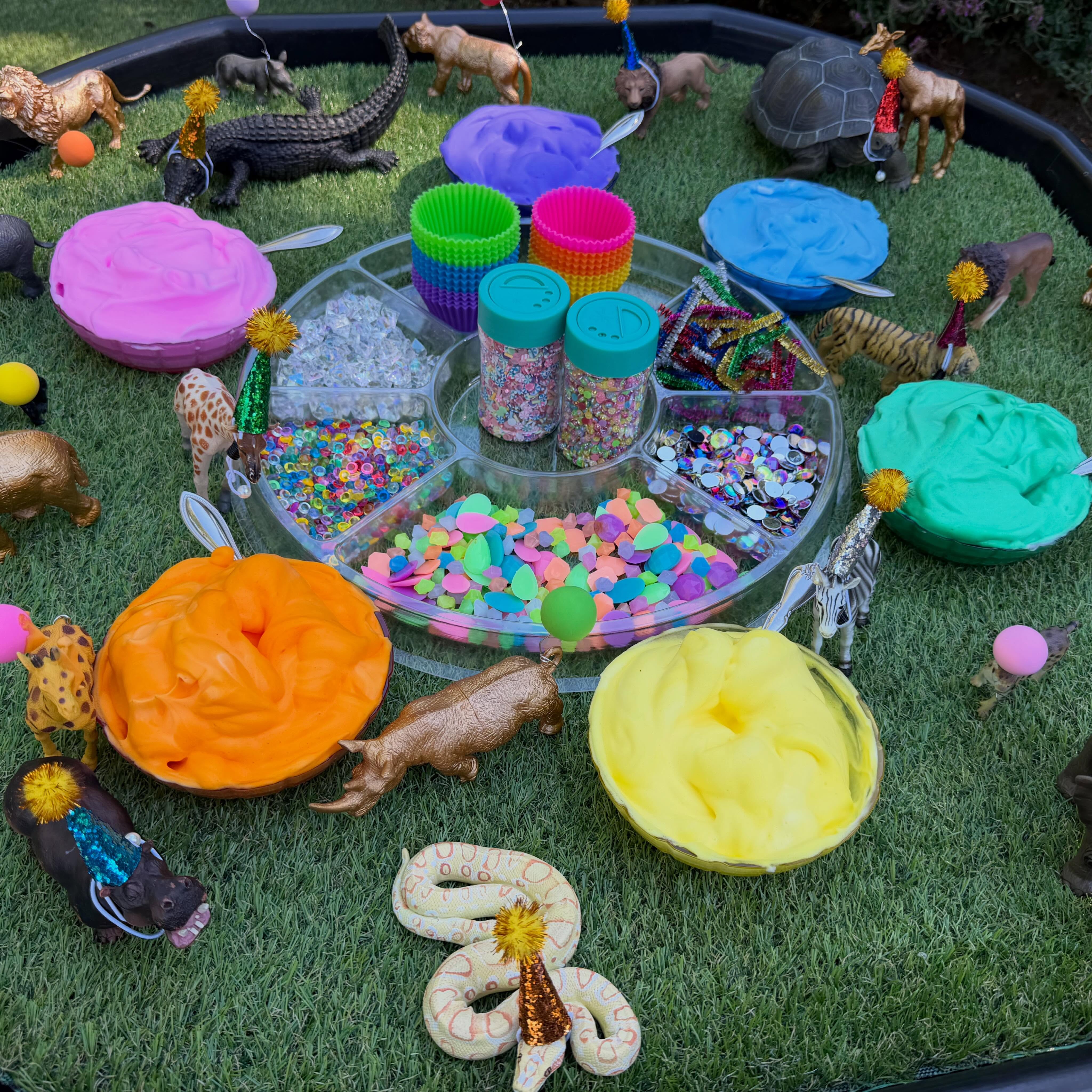 Party Animals: A Sensory Cupcake Invitation// There’s a party about to begin, & all of the party animals are waiting for one very important thing... cupcakes! This playful sensory invitation invited children to become little bakers as they created colorful cupcake masterpieces filled with creativity & imagination.
To set up the invitation, we placed party animal figurines with mini party hats & balloons in our @discountschoolsupply tuff tray with the grass playmat insert. Children were provided with cupcake liners filled with fluffy shaving cream mixed with vibrant @colorationsart Liquid Watercolors, creating “frosting” that was irresistible to swirl, scoop, & decorate.
Our Tinker Tray held an exciting assortment of loose parts including resin sprinkles, acrylic rocks, pipe cleaners, & gems galore, giving children endless opportunities to design unique sensory cupcakes.
As children scooped, swirled, pinched, pressed, & placed the loose parts into the shaving cream, they strengthened the small muscles in their hands, refined hand-eye coordination, & developed the fine motor control. The soft sensory frosting also provided a rich tactile experience, encouraging children to explore texture + cause & effect as they experimented with different ways to decorate.
Beyond the sensory benefits, this invitation naturally encouraged creativity, storytelling, & imaginative play. Children assigned cupcakes to different animals, described birthday celebrations, sang songs, counted decorations, compared sizes, created patterns with their loose parts, & invented their own party adventures. These playful conversations strengthened language development, sequencing skills, & early math concepts in an authentic & meaningful way.
Sometimes the most memorable invitations begin with a simple story or problem to solve. In this case, a group of party animals simply needed someone to bake the cupcakes, & the children were more than ready to make the celebration unforgettable. #tinkerwonderplay #tufftrayideas #tufftrayplay #sensoryplayideas #sensoryplaytime